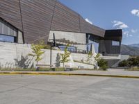 the concrete walkway has a railing that extends the building's roof onto the mountains