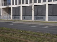 this is an empty sidewalk in front of a building with closed doors and blinds on it