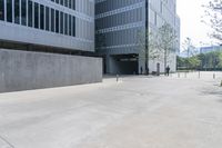 a grey concrete wall near a building in the daytime sunlight with benches in the foreground