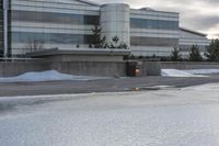 the building is next to a garbage can and snow on the ground area of the courtyard