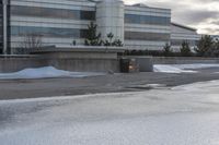 the building is next to a garbage can and snow on the ground area of the courtyard