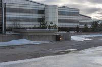 the building is next to a garbage can and snow on the ground area of the courtyard