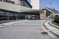 a person sitting at the bench in front of a mall that is empty of people