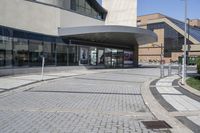 a person sitting at the bench in front of a mall that is empty of people