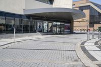 a person sitting at the bench in front of a mall that is empty of people