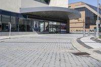 a person sitting at the bench in front of a mall that is empty of people