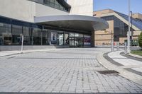 a person sitting at the bench in front of a mall that is empty of people