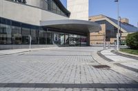 a person sitting at the bench in front of a mall that is empty of people