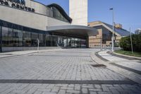 a person sitting at the bench in front of a mall that is empty of people