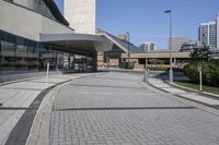 a person sitting at the bench in front of a mall that is empty of people