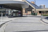 a person sitting at the bench in front of a mall that is empty of people