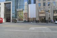 a double decker bus and taxi stopped at the intersection of a street and a glass office building