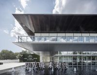 the entrance to a building with water in front and people around it with clouds overhead