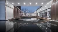 a reflection of a building on top of water with lights coming from it's window