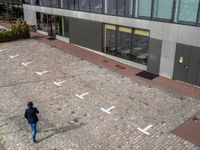 a man walking down a street near a building that has numbers on it, one number is white