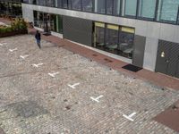 a man walking down a street near a building that has numbers on it, one number is white