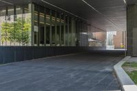 the view of an overpass under a building with grass and a bench in it