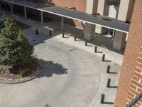 a group of people walking across a cement courtyard next to a brick building and walkway