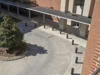 a group of people walking across a cement courtyard next to a brick building and walkway