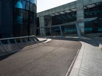 a skateboarder is going around on a sidewalk near a big building's glass windows