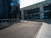 a skateboarder is going around on a sidewalk near a big building's glass windows