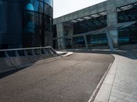 a skateboarder is going around on a sidewalk near a big building's glass windows