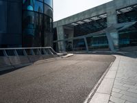 a skateboarder is going around on a sidewalk near a big building's glass windows