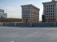 several large empty parking spaces in the city with buildings nearby in front of them -