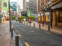 a narrow city street lined with high rise buildings and green and yellow flags on poles