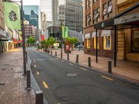 a narrow city street lined with high rise buildings and green and yellow flags on poles