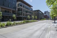 a street with several building in it, with people walking on the side walk and trees on both sides