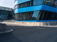 a skateboarder is going on an empty road near a building with glass windows