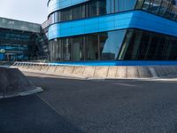 a skateboarder is going on an empty road near a building with glass windows