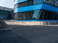 a skateboarder is going on an empty road near a building with glass windows