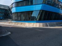 a skateboarder is going on an empty road near a building with glass windows