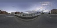 a 360 - pane view of a bridge across the street at dusk, with a traffic light