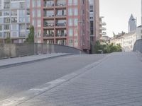 the sidewalk by the street is empty and sun shines on it and the city has very tall buildings in front