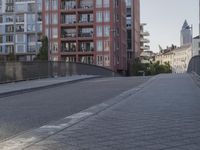 the sidewalk by the street is empty and sun shines on it and the city has very tall buildings in front