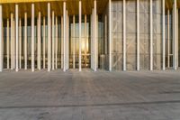 a view of a glass and gold building from inside the building, a bench is in front