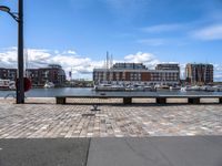 several benches near each other by the water with boats in it and some buildings in the background