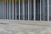 a building that has a large number of columns around it on the sidewalk outside of the room