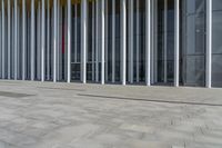 a building that has a large number of columns around it on the sidewalk outside of the room