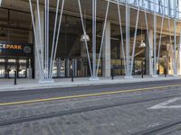 a train tracks near a public space with people walking by it and some glass walls