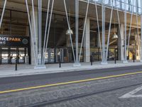 a train tracks near a public space with people walking by it and some glass walls