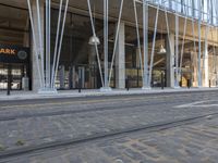 a train tracks near a public space with people walking by it and some glass walls