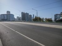 city buildings are on the side of a highway in the daytime, the street is empty and there is an empty road near it