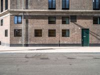 a green door is open to the street near a building, as it's sunny and empty