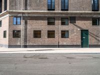 a green door is open to the street near a building, as it's sunny and empty