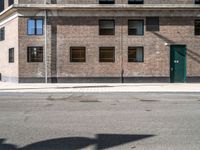 a green door is open to the street near a building, as it's sunny and empty