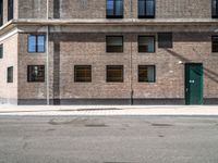 a green door is open to the street near a building, as it's sunny and empty